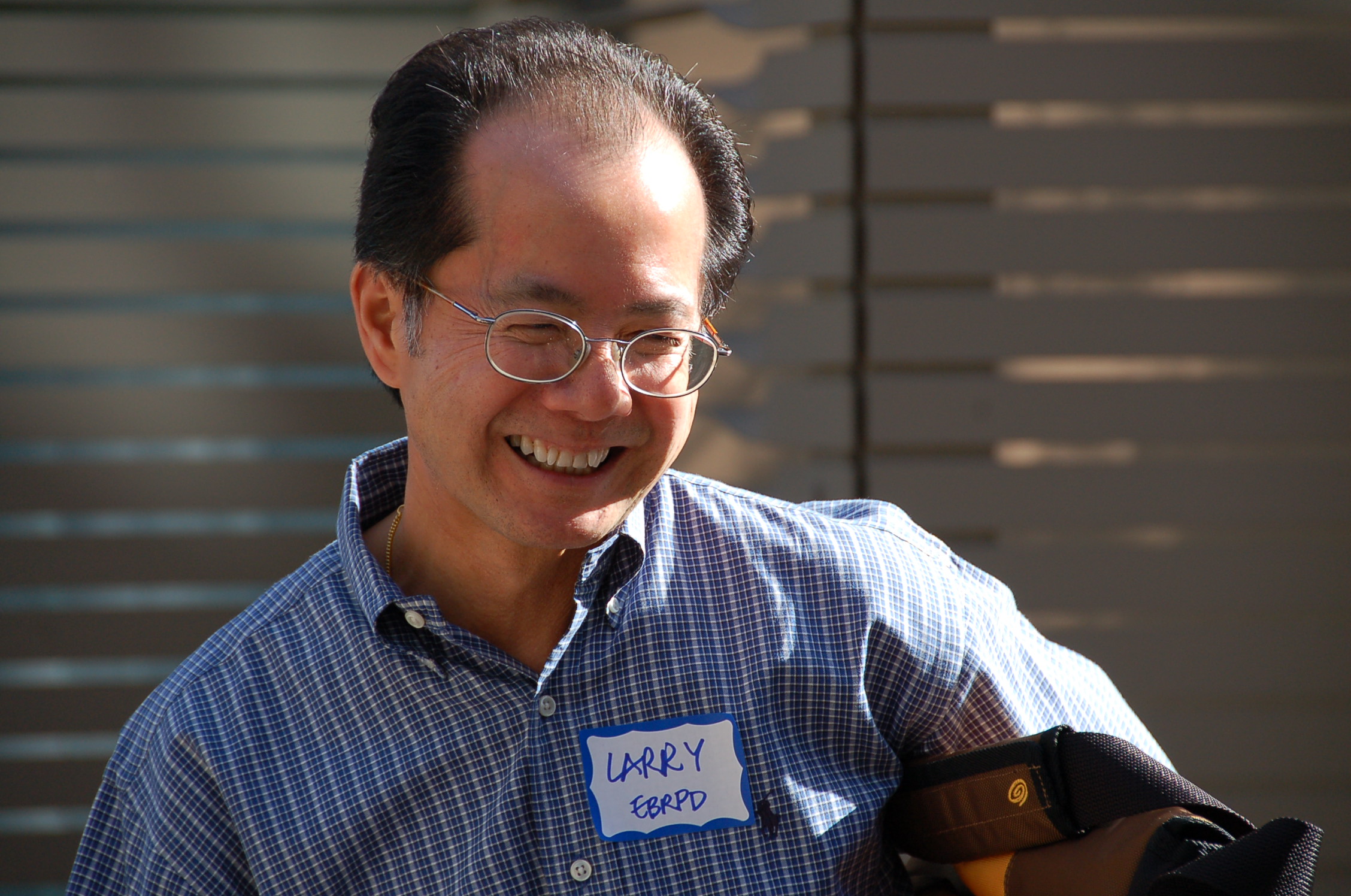 an older asian man in a blue shirt smiling at the camera
