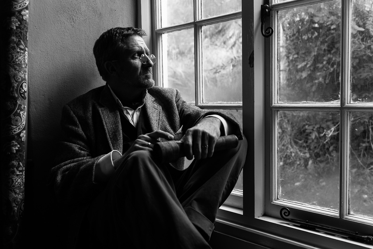a black and white po of a man sitting next to a window