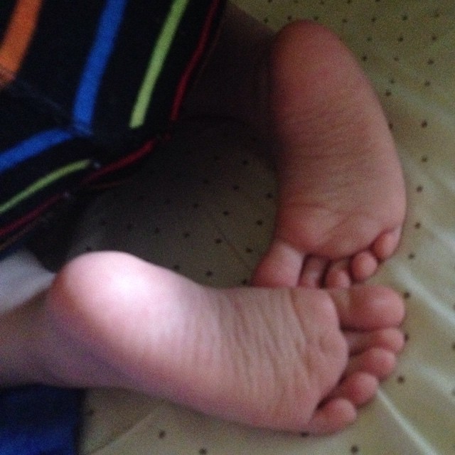 the feet of a little boy laying down on a bed