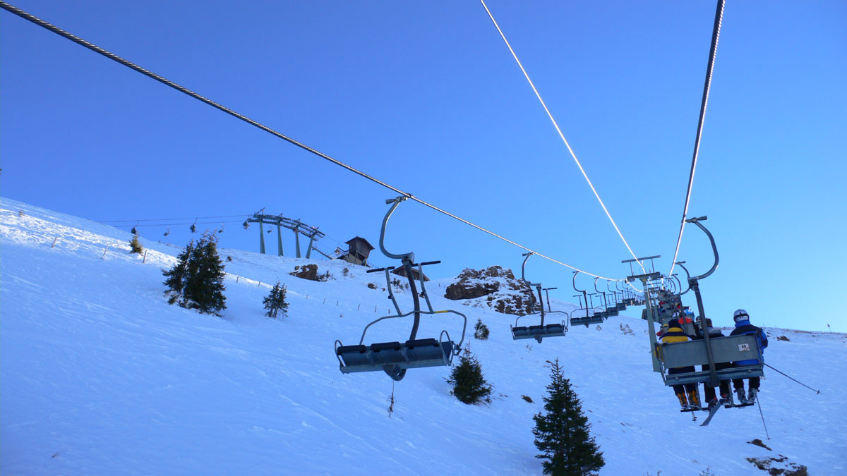 a chairlift is carrying skiers up a snowy hill