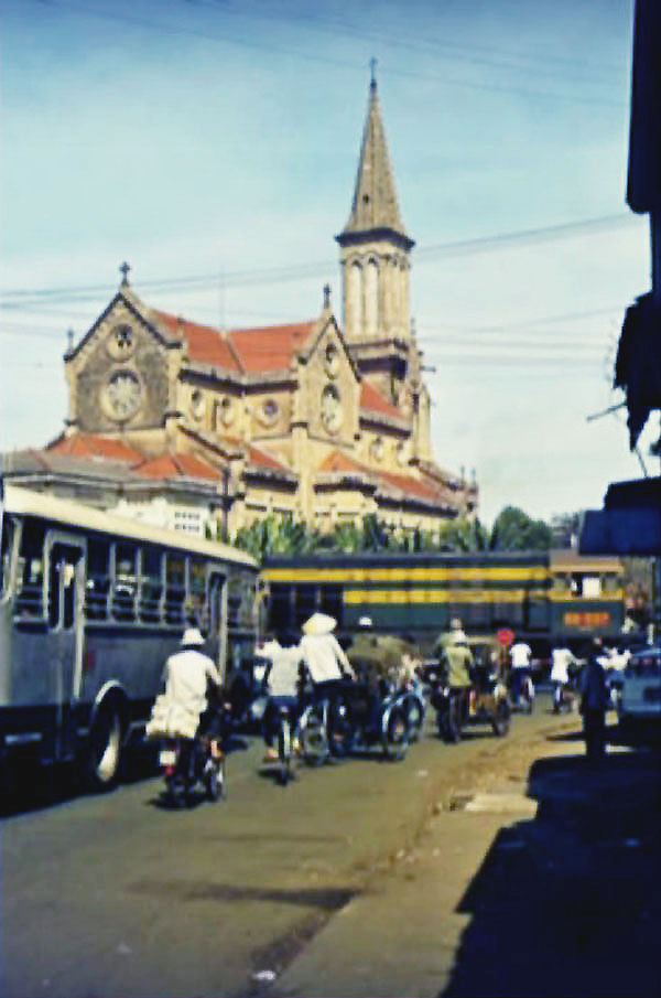 people riding bicycles down a street near a church