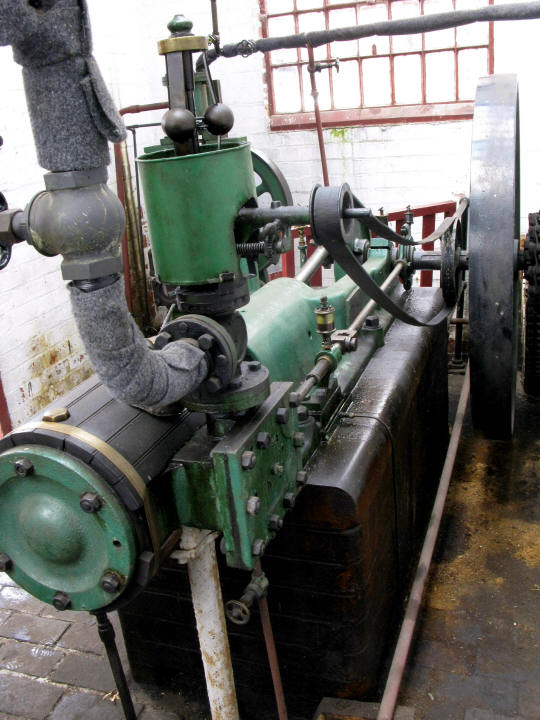 a old green machine with multiple pipes and a pipe holder