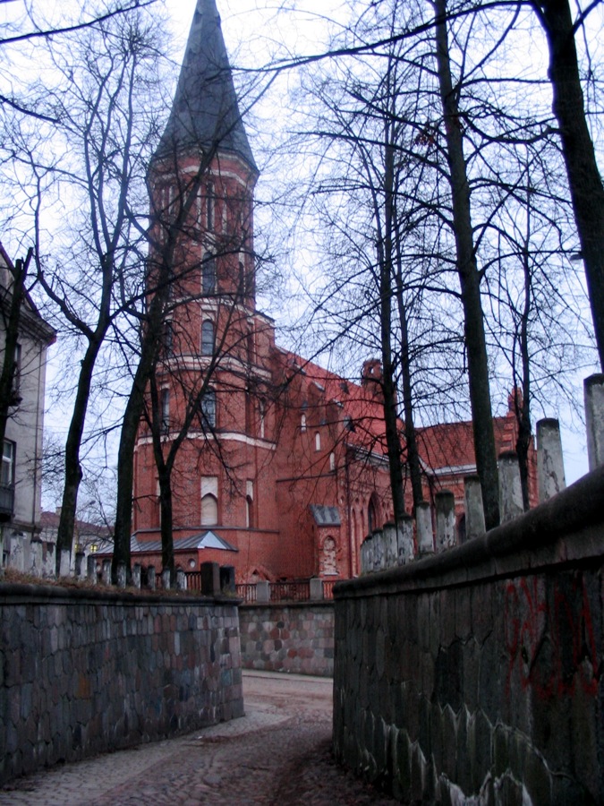 a stone fence with a tall red building in the background