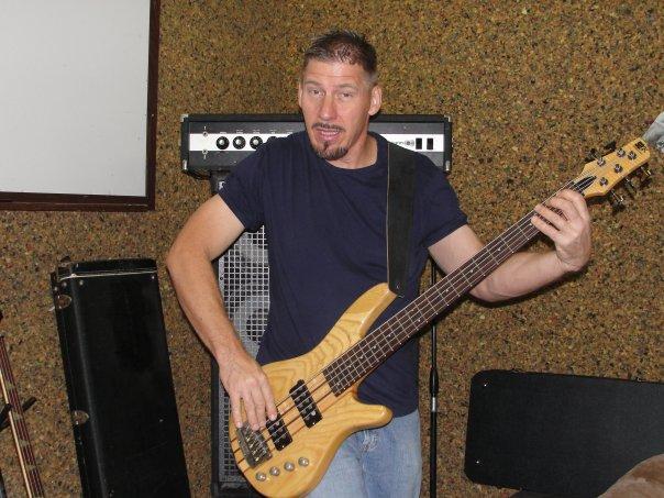 a man is holding an electric bass guitar
