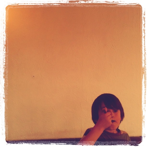 a boy brushing his teeth while sitting in front of the mirror