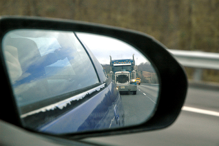 a mirror reflecting the view of a truck in another vehicle's side view mirror