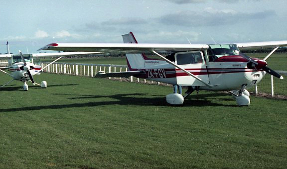 two airplanes sitting on a lush green field