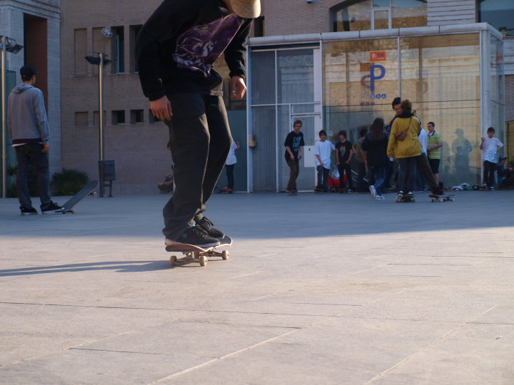 a young man rides on a skateboard in a courtyard