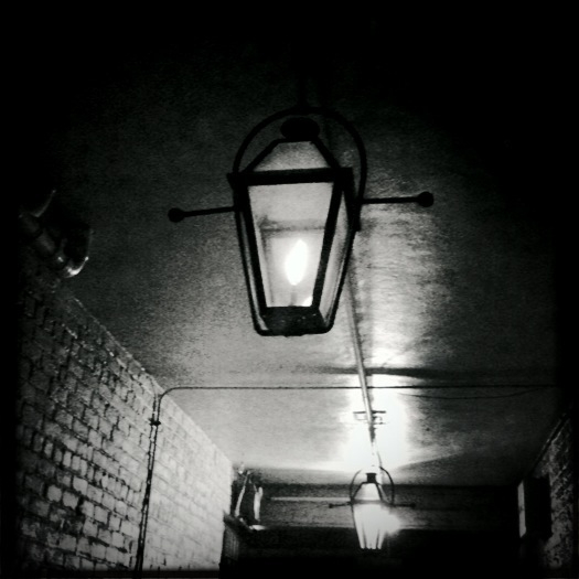 an old light hangs on a brick wall