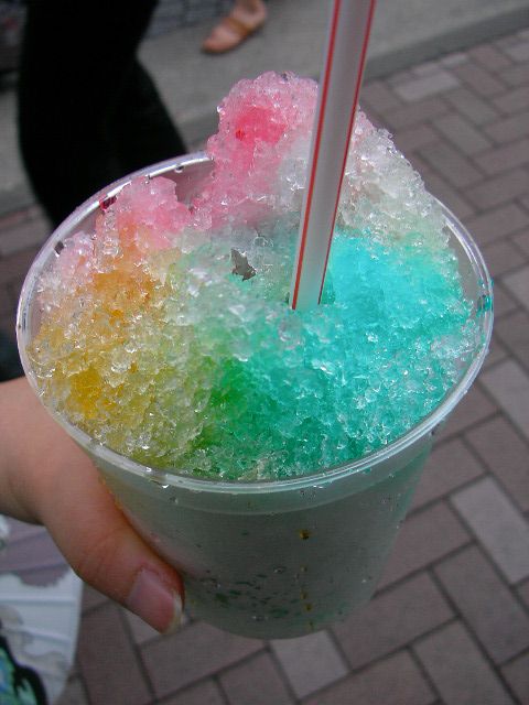 a hand is holding a drink with colorful, sprinkled ice