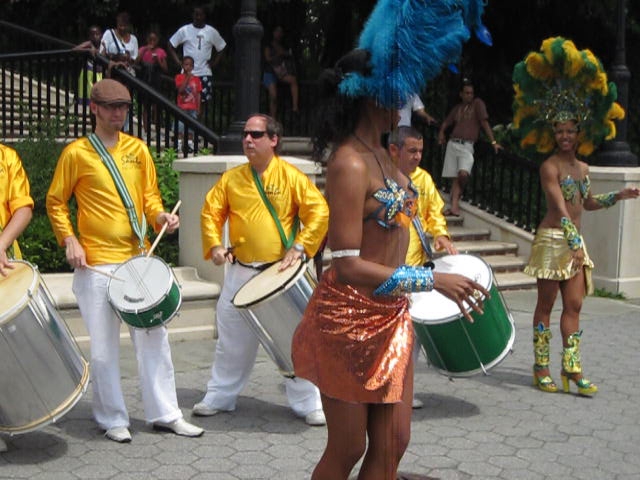 men in yellow shirts and white pants are holding drums