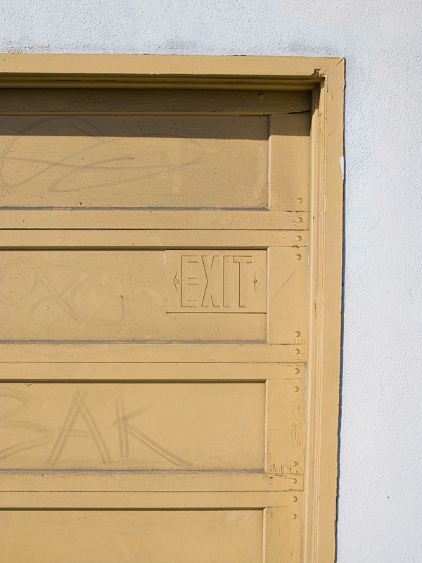 a large door to a white building with a street sign