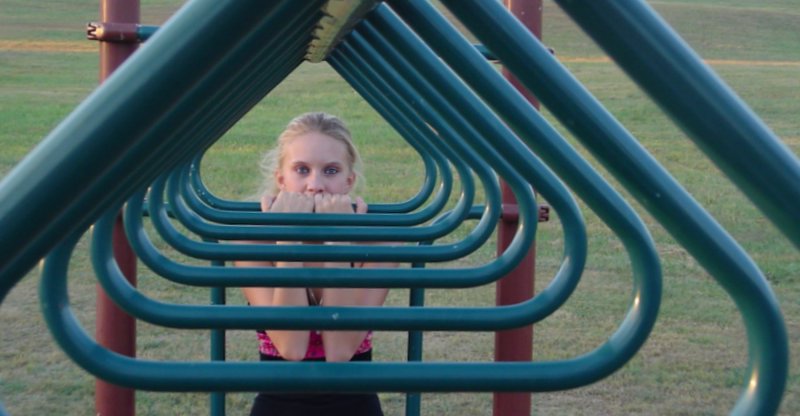 a woman is peeking out from behind several metal swings
