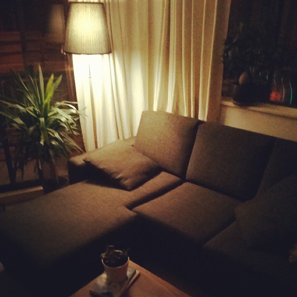 a brown sectional couch sitting in a living room under a lamp