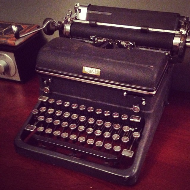 a desk with an old fashioned black typewriter