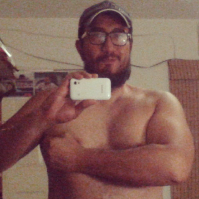 a shirtless man taking a selfie in front of his mirror
