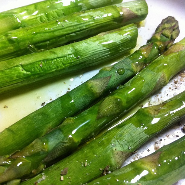 the asparagus are covered with olive oil and other seasonings