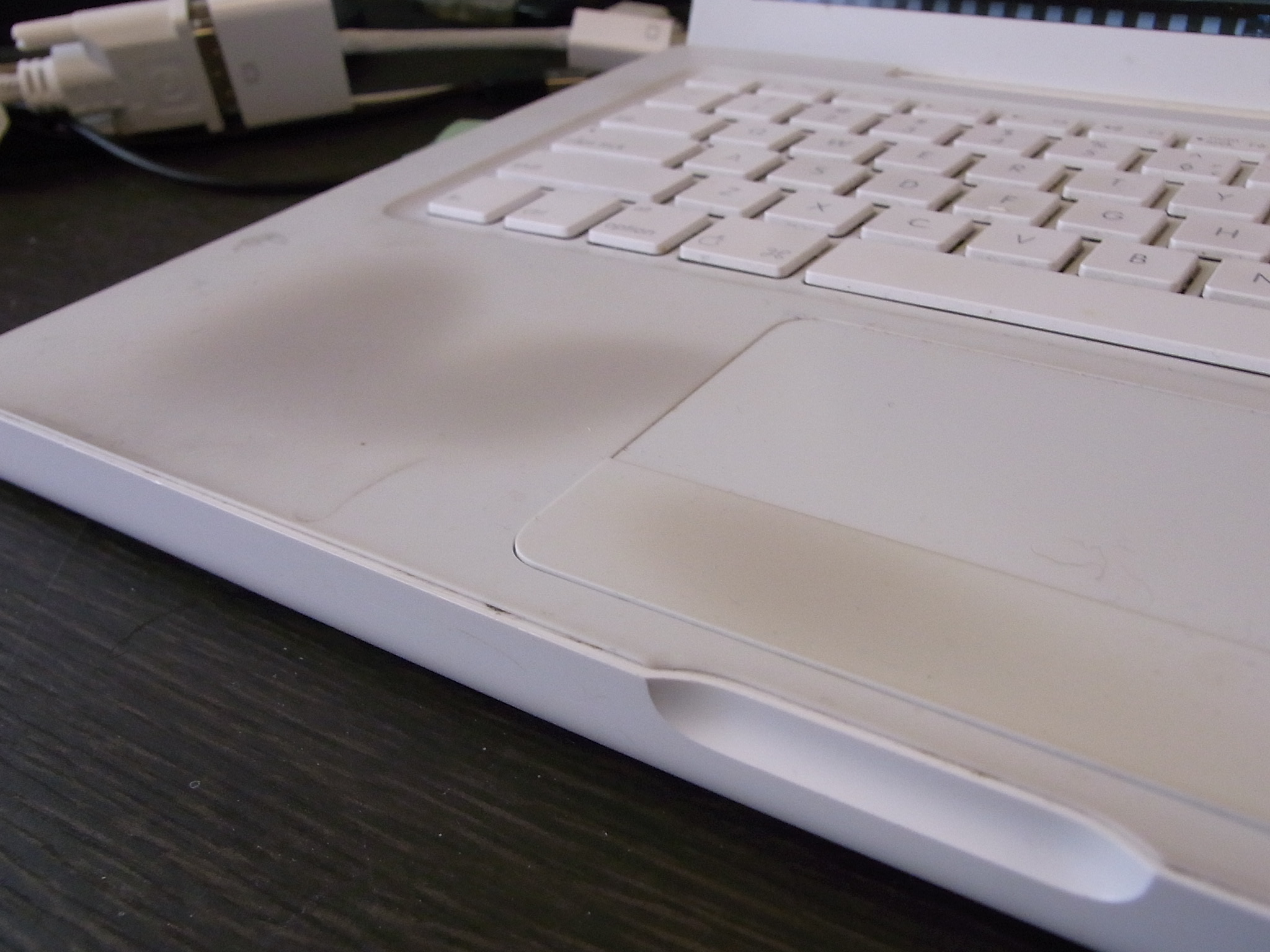 a white laptop with a white keyboard and two yellow wires