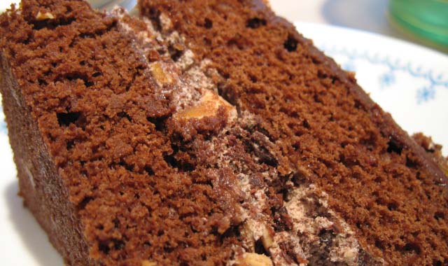 a piece of chocolate cake on a plate with nuts