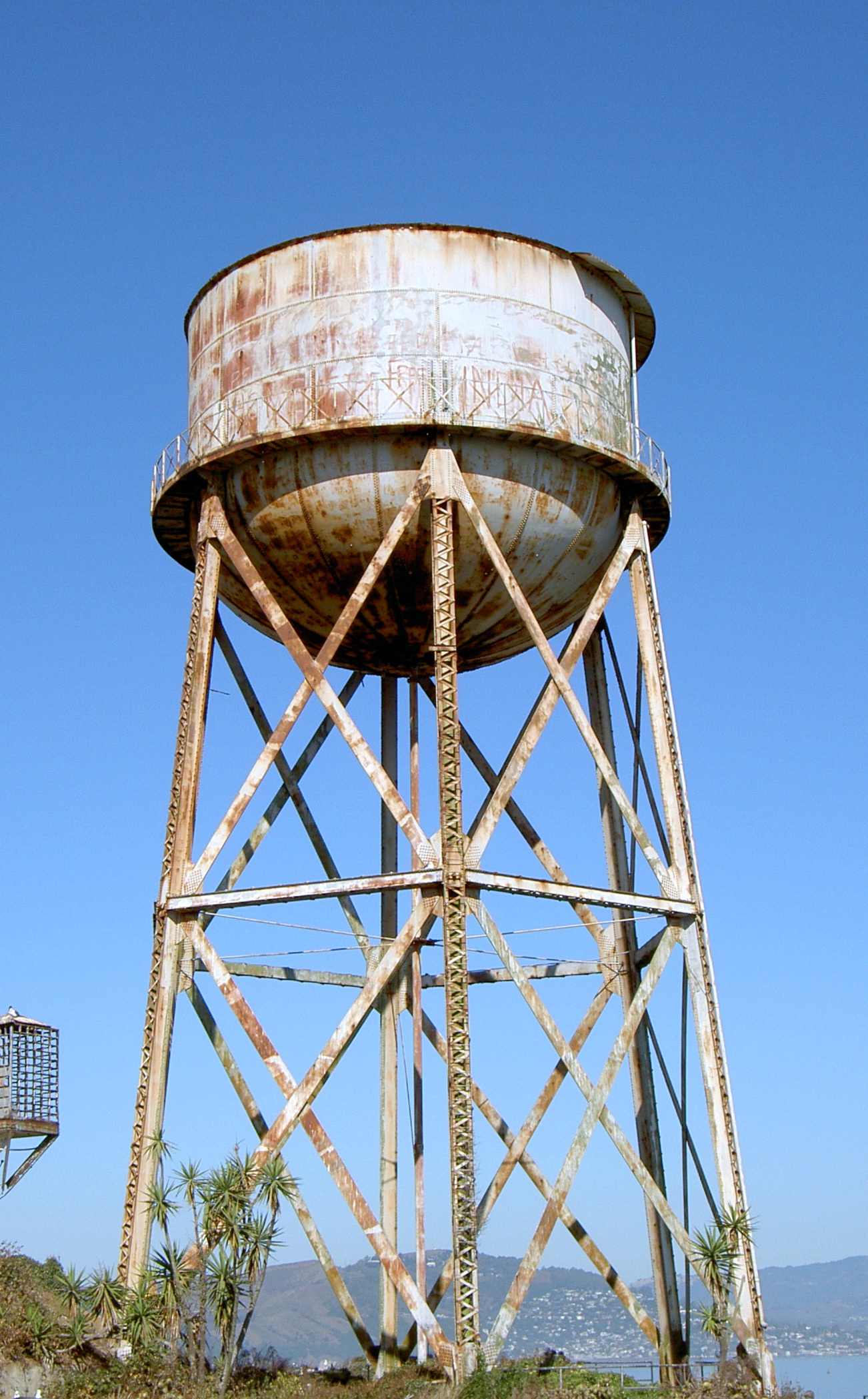 a rusty looking water tower sitting on top of a hill