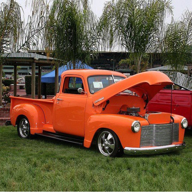 an orange truck is parked by some trees