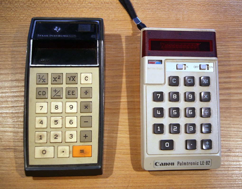 two old calculators sitting on a table