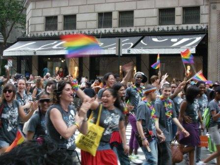 a large group of people walk along the street while waving rainbow flags