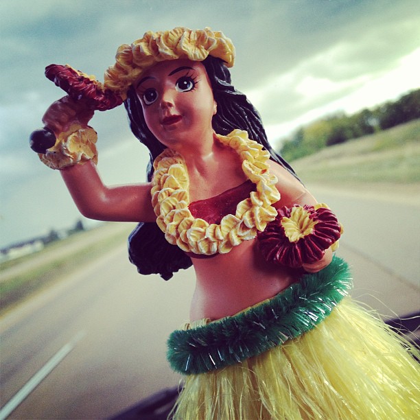 doll posed in costume on a vehicle dashboard