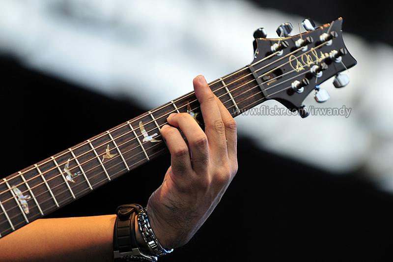 a person with their hands on the strings of a guitar