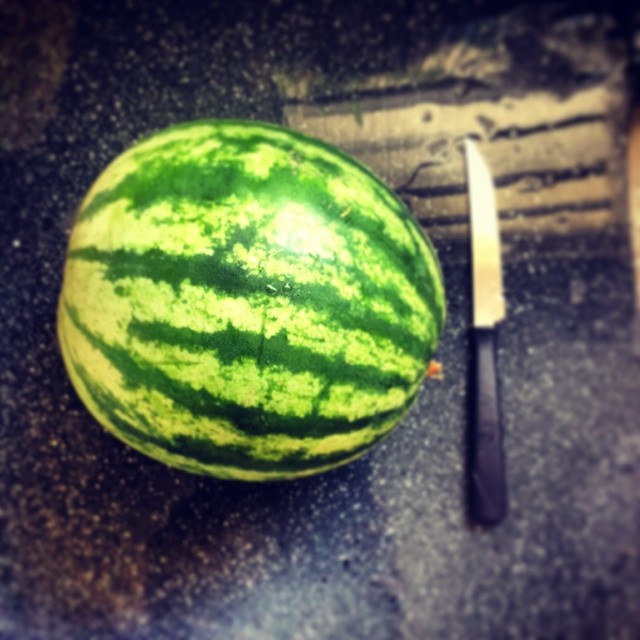 a watermelon is next to a knife on a table