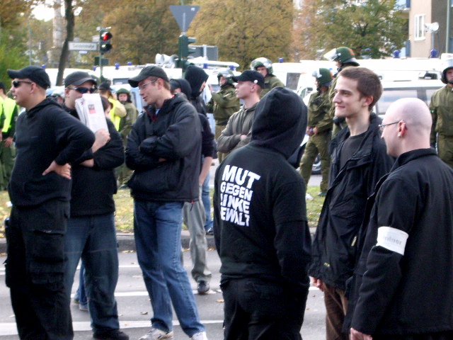 a group of protesters standing around a street corner