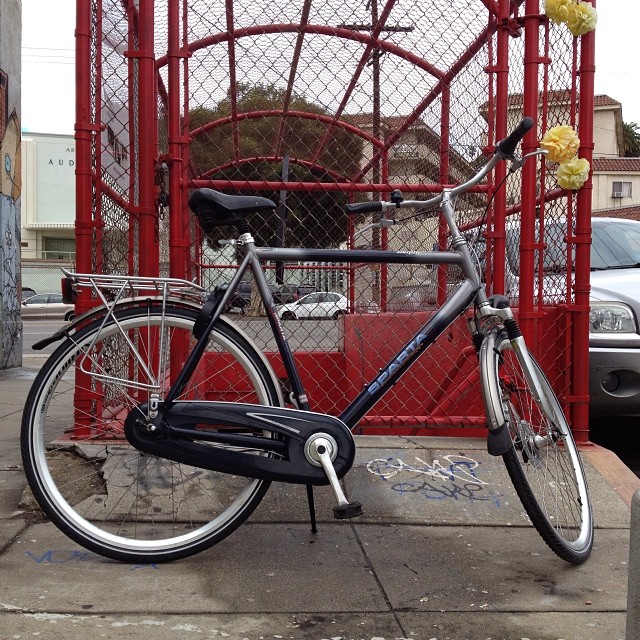 bicycle  to a gate on the side of the street