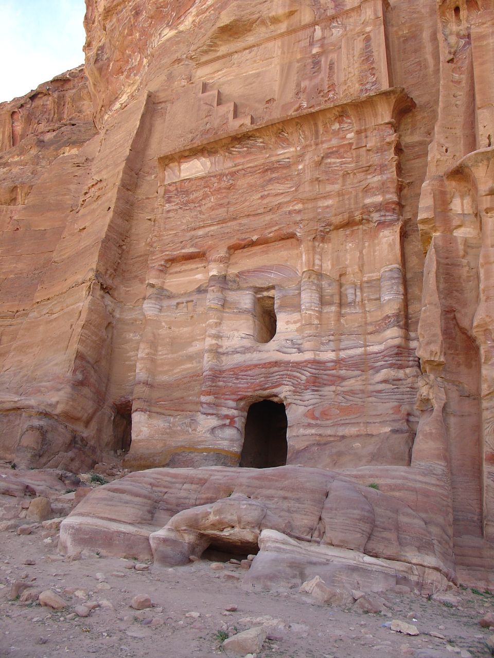 a man is walking through a narrow doorway in the side of a cliff