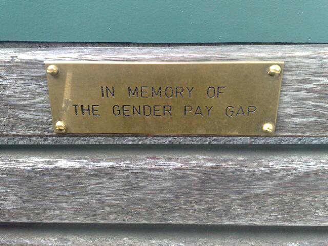 a plaque is displayed on the back of a wooden bench