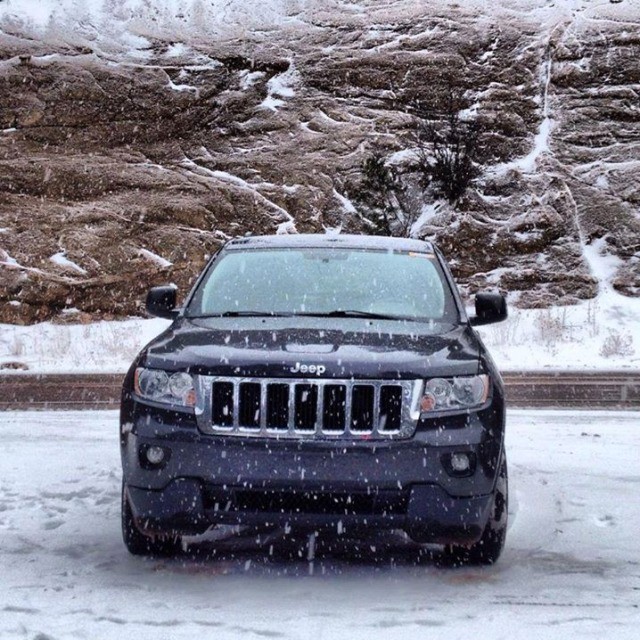 a black jeep parked in front of a stone wall