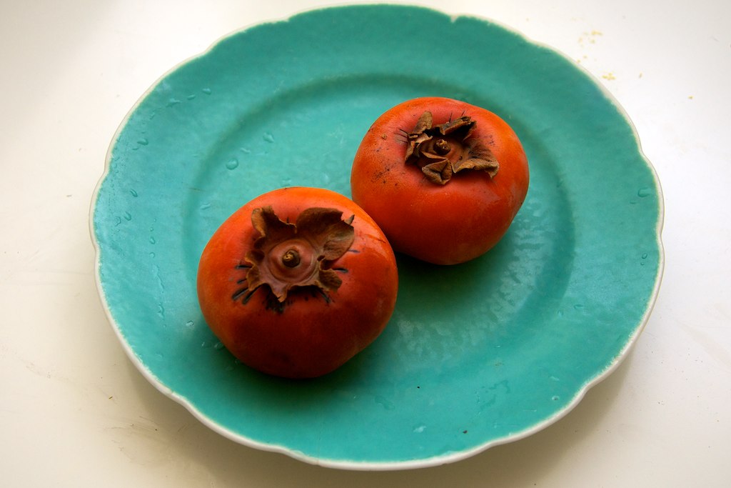 two tomatoes sitting on a turquoise plate that's on the table