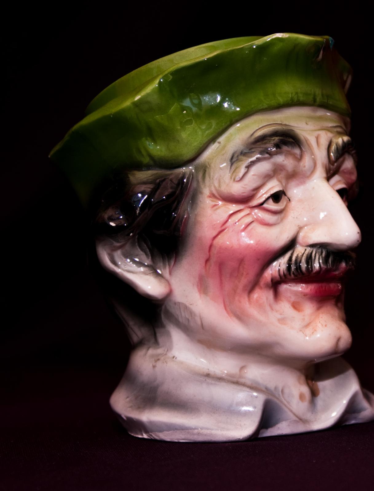 a close up of a green hat on a ceramic bust
