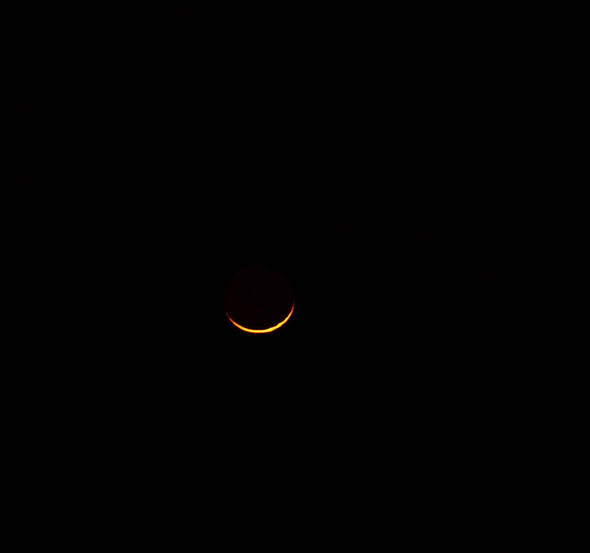 the moon in a darkened sky with a light from nearby