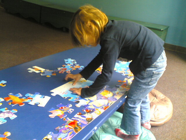 a little girl playing with jigsaw on the floor