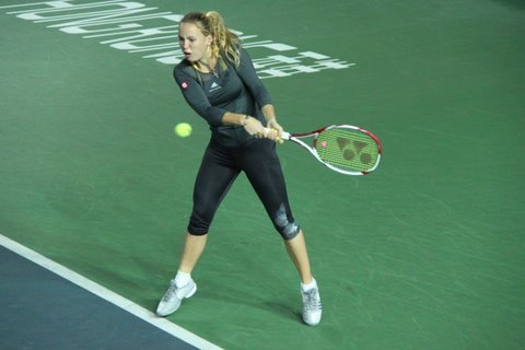 a tennis player in black outfit playing tennis