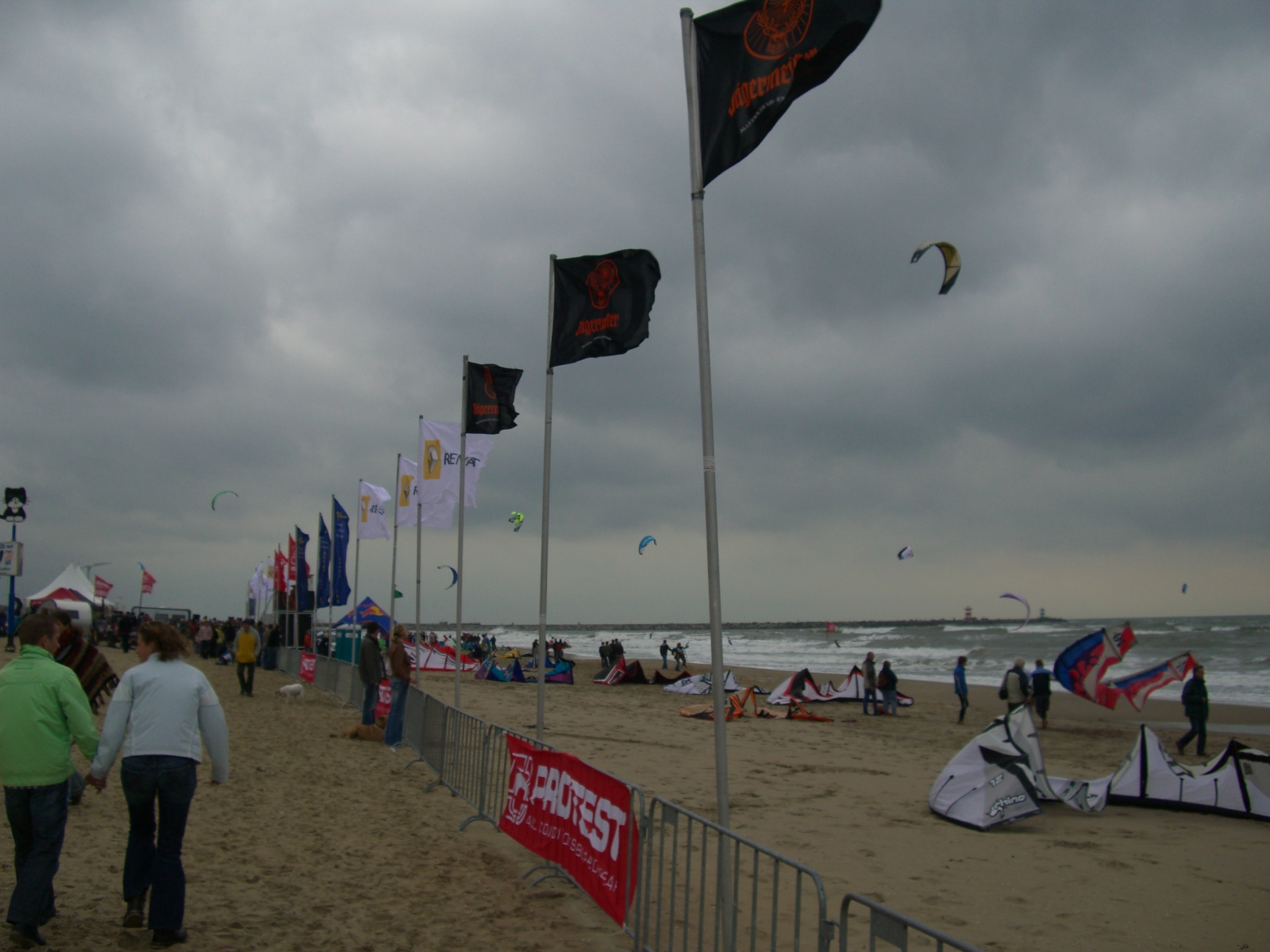 people on a beach with flags flying in the sky