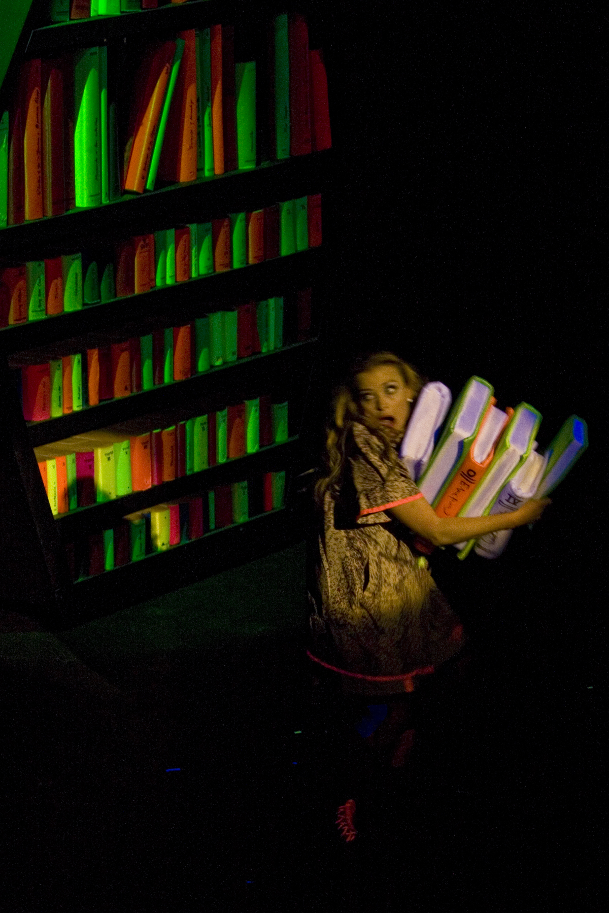 a woman holding several skate boards and a book case