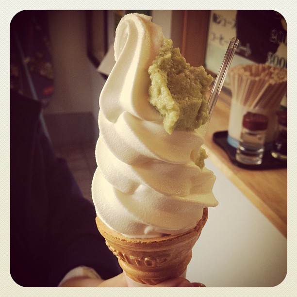 a person holds an ice cream cone with green toppings
