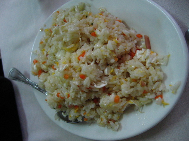 a plate with rice and carrots on a white table