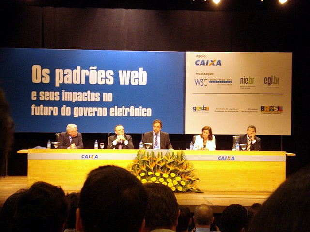 people at a conference sitting at desk in front of the camera