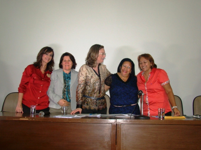 a group of women smiling next to each other in front of a conference table