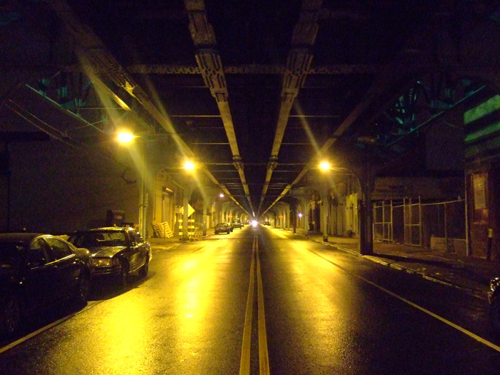 a night scene looking down a dark street with car passing