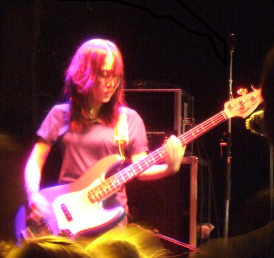 woman holding bass guitar on stage at event