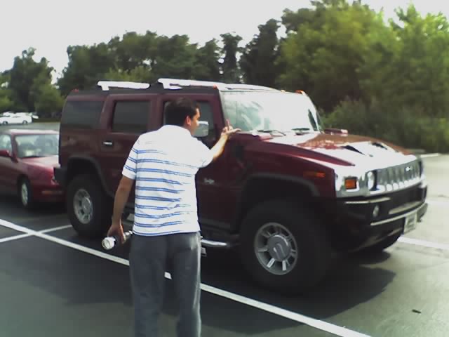 man standing in parking lot touching car door