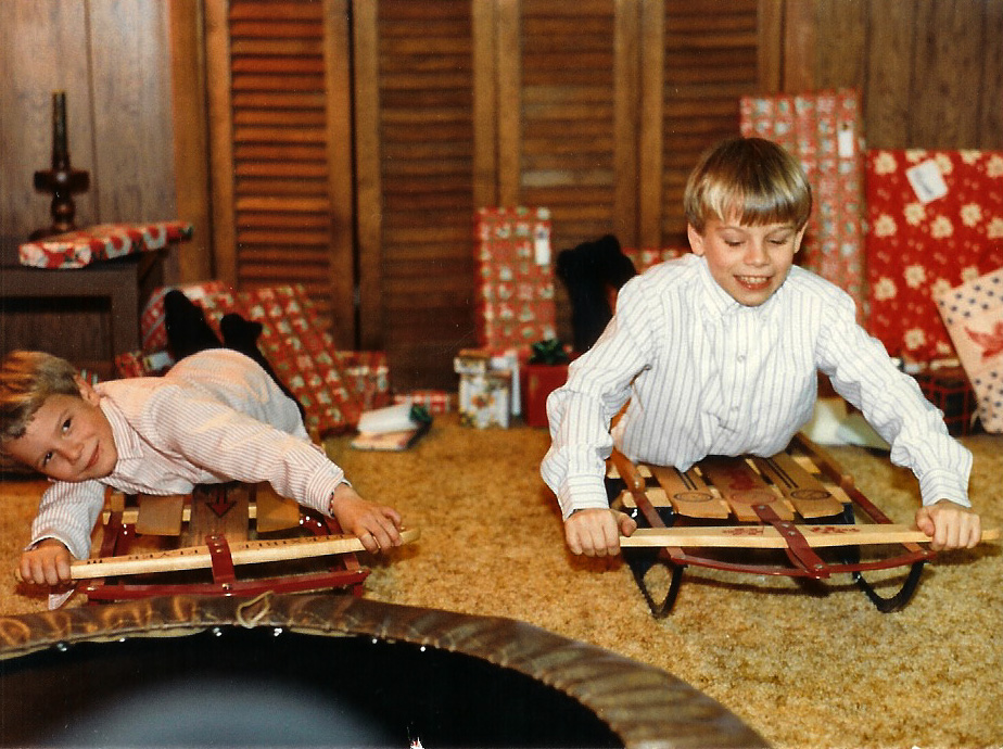 two young children play with sleds while another watches